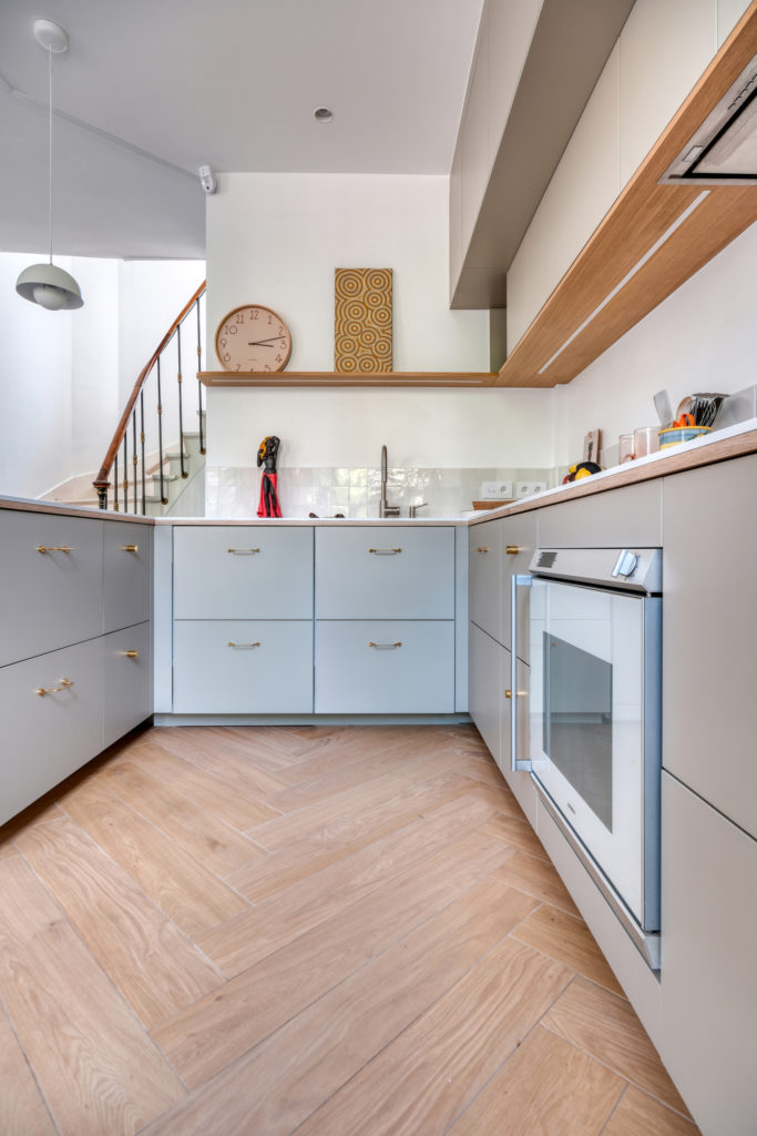 Aménagement d'une cuisine en U sur mesure avec crédence en zelliges et tablettes en bois dans une maison meulière à Versailles