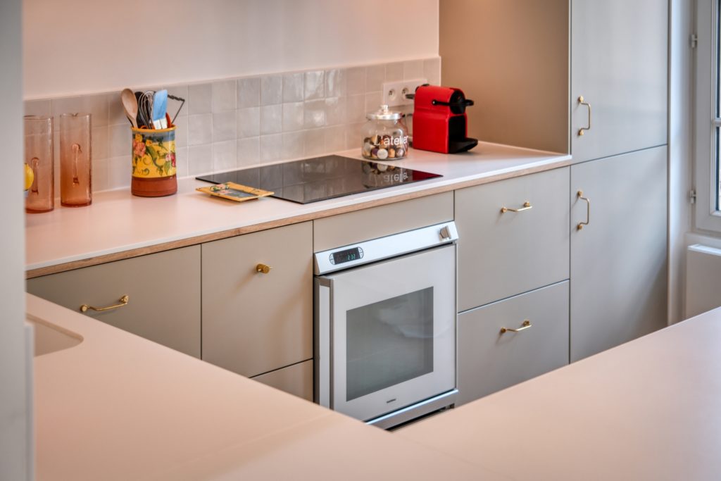 Aménagement d'une cuisine en U sur mesure avec crédence en zelliges et tablettes en bois dans une maison meulière à Versailles