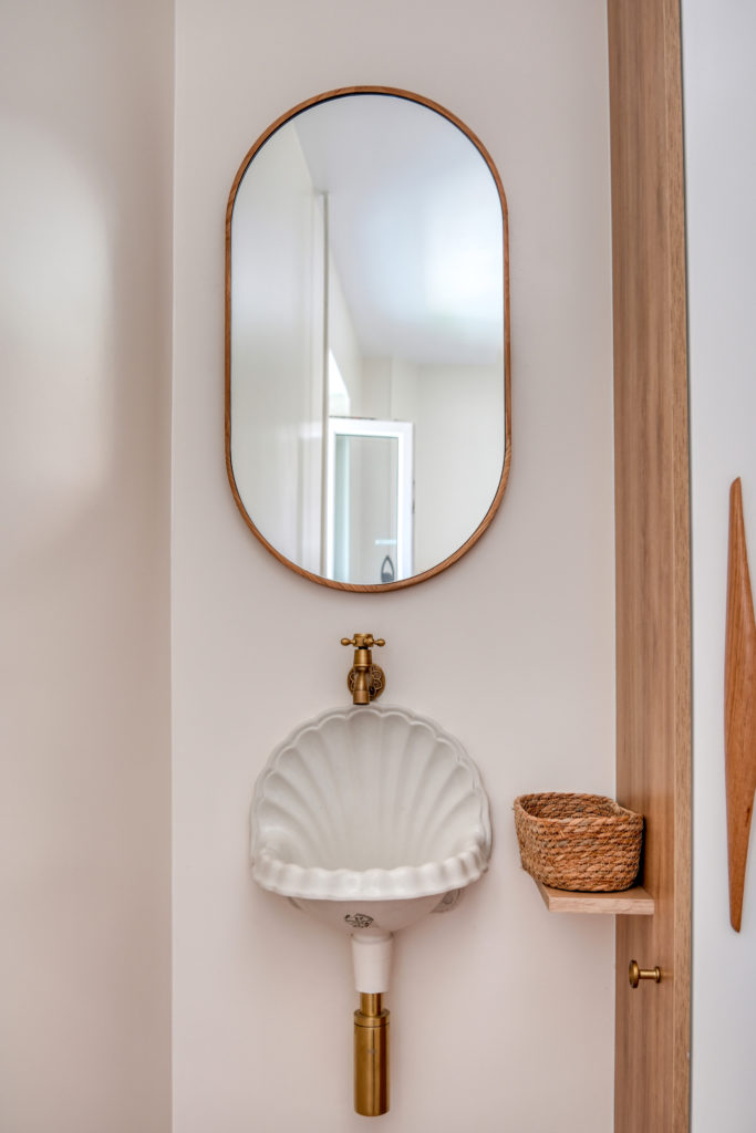 Détail des toilettes : vasque rétro en forme de coquillage et robinetterie dorée