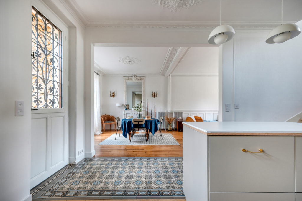Rénovation d'une maison meulière à Versailles par Agence Avous : vue de l'entrée avec carreaux de ciment d'origine rénovés et transition vers le parquet