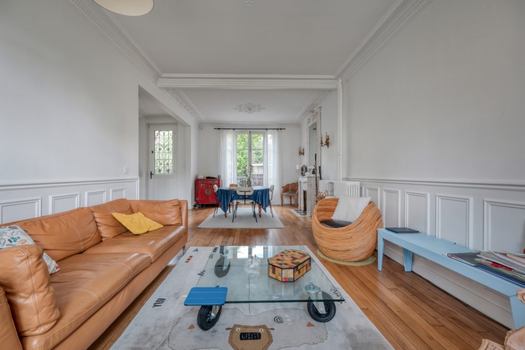 Salon et salle à manger d'une maison ancienne autour d'une cheminée en marbre d'origine et ouvertures sur l'extérieur