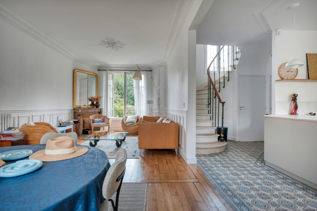 Salon et salle à manger d'une maison ancienne autour d'une cheminée en marbre d'origine et ouvertures sur l'extérieur