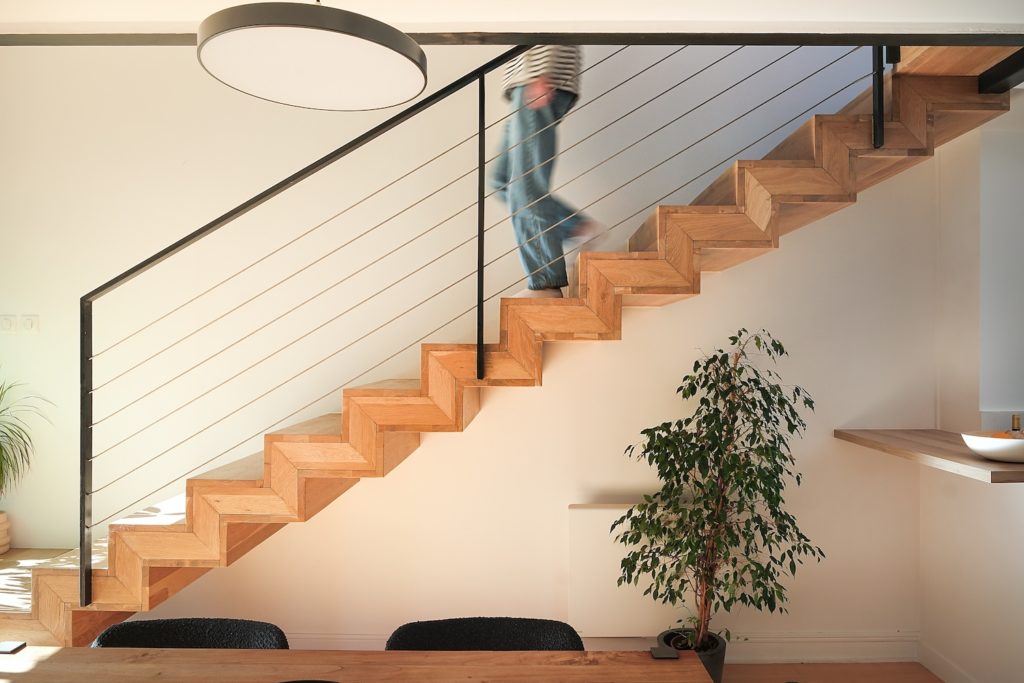 Escalier en bois menant aux combles et coin repas baigné de lumière naturelle