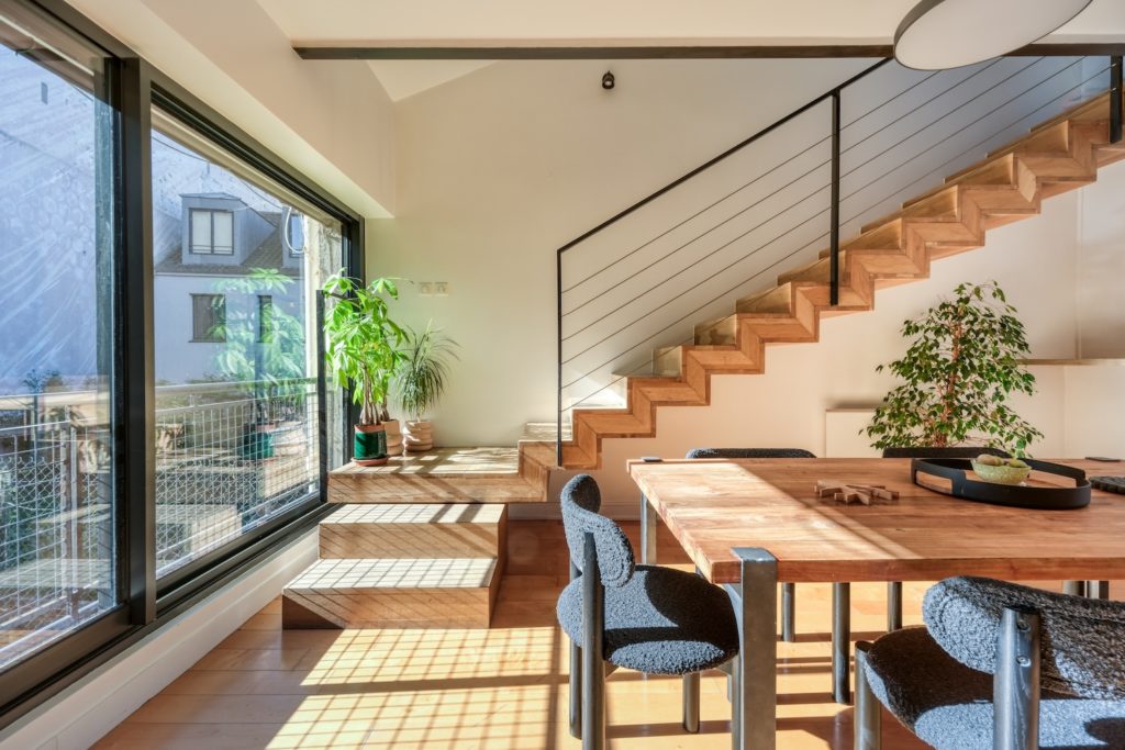 Escalier en bois menant aux combles et coin repas baigné de lumière naturelle