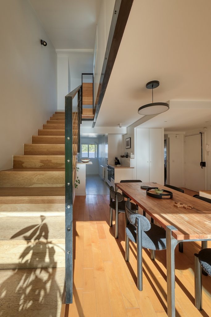 Escalier en bois menant aux combles et coin repas baigné de lumière naturelle