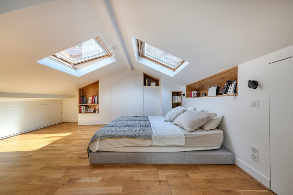 Chambre sous combles avec grand dressing sur mesure blanc et niche de tête de lit en bois