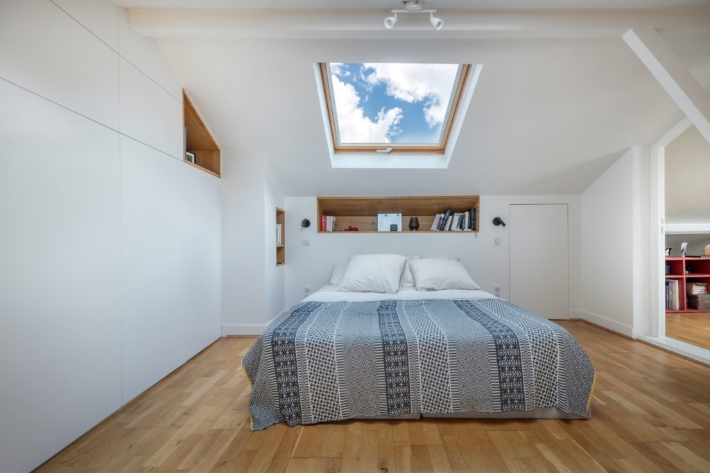 Chambre sous combles avec grand dressing sur mesure blanc et niche de tête de lit en bois