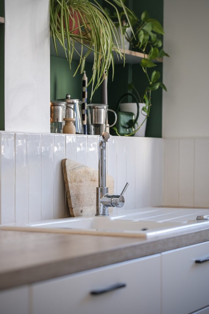 Cuisine ouverte sur le séjour avec plan de travail en bois, crédence claire et niches murales peintes en vert