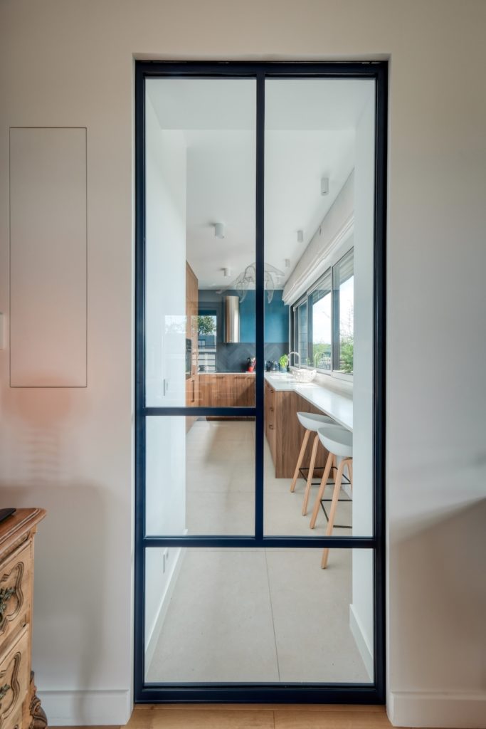 Porte verrière coulissante type atelier séparant la cuisine tout en laissant passer la lumière